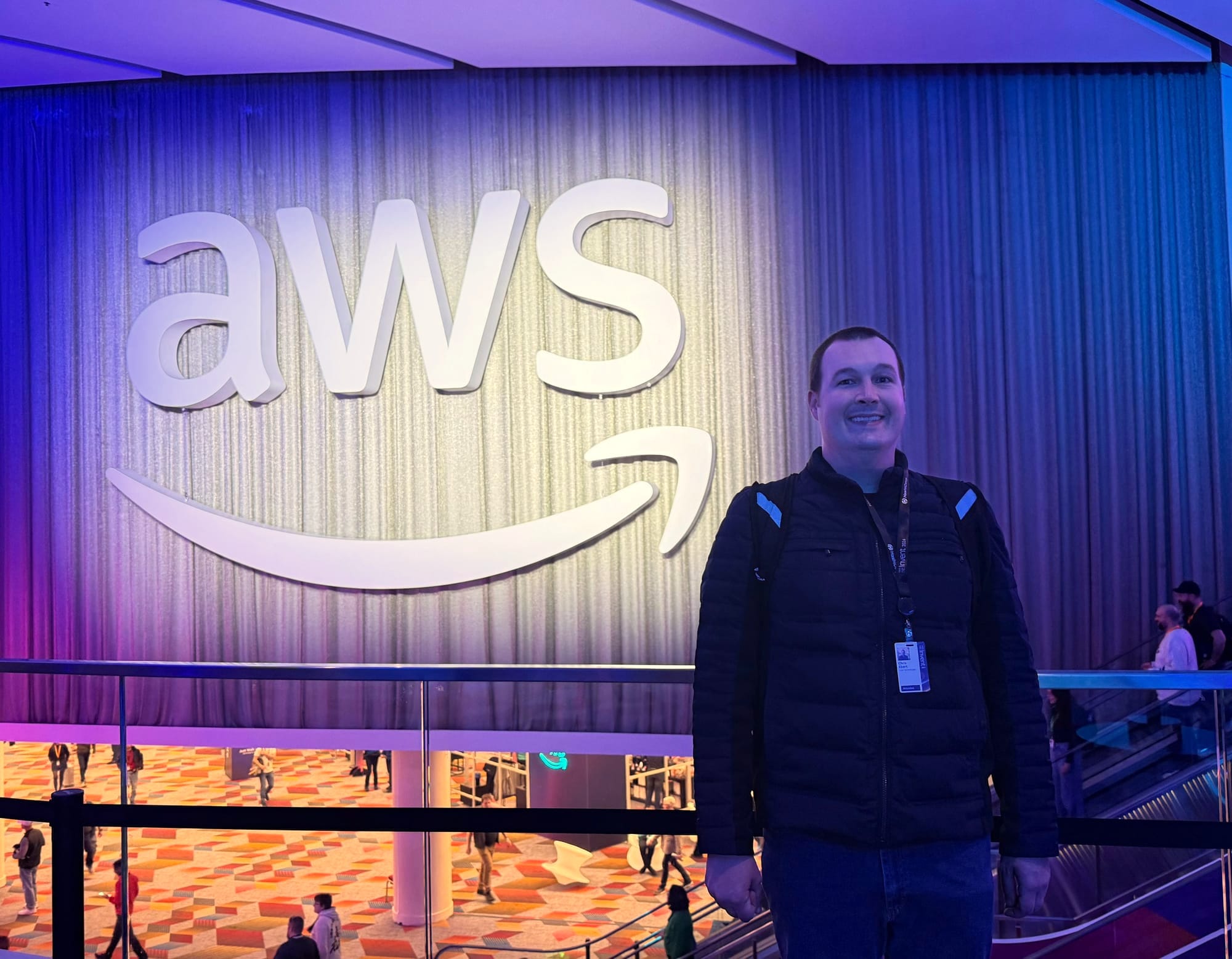 A A picture of Chris Ebert sending in front of a large AWS logo at the AWS re:Invent 2024 conference